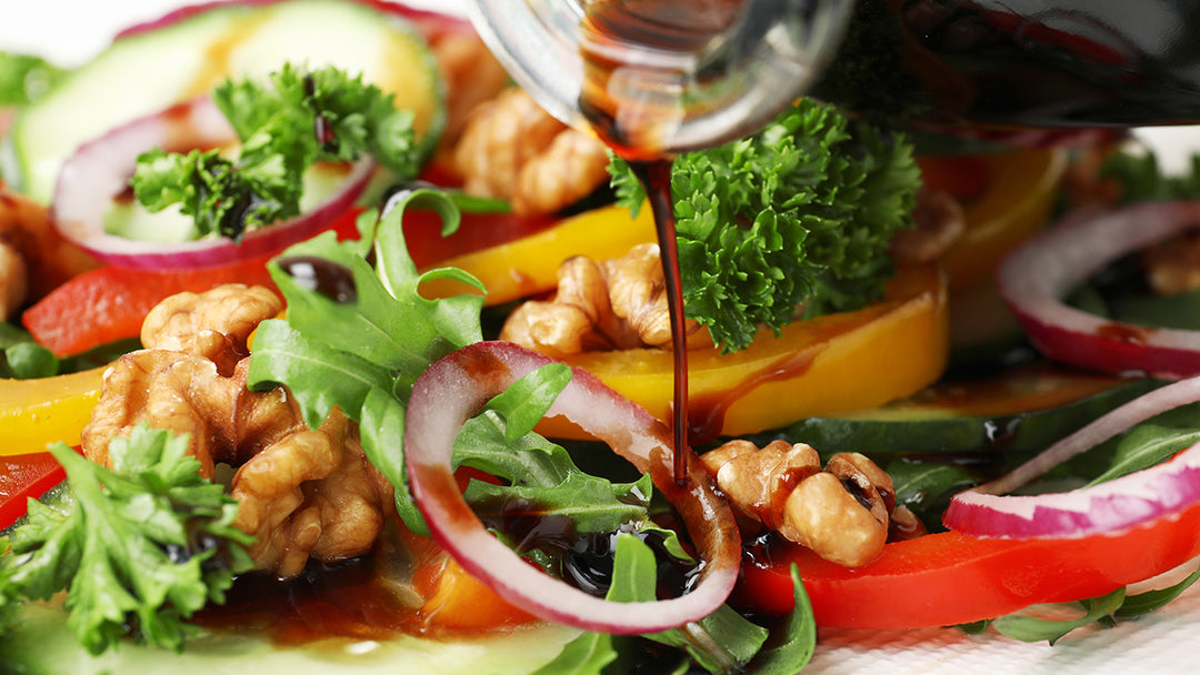 Maple Balsamic Vinegar being poured on a fresh garden salad.